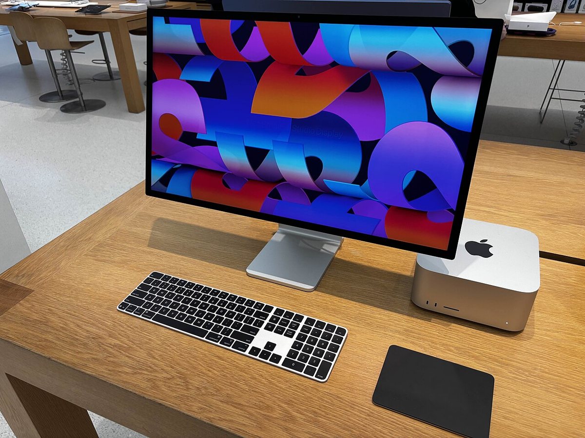 A Mac Studio, Studio Display, keyboard, and trackpad on a wooden desk