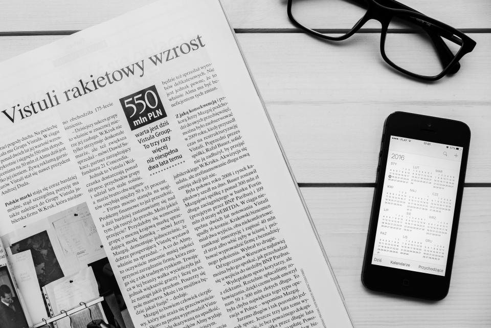 A printed newspaper and a smartphone on a table