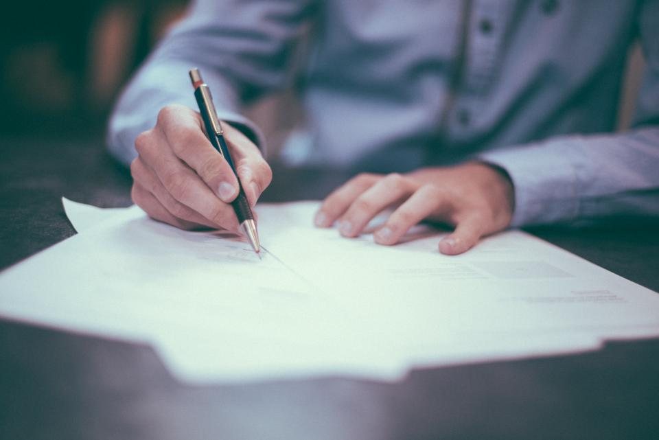 A hand editing text with a pen on white paper