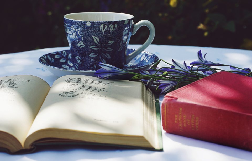 A book of poems lying open beside a teacup