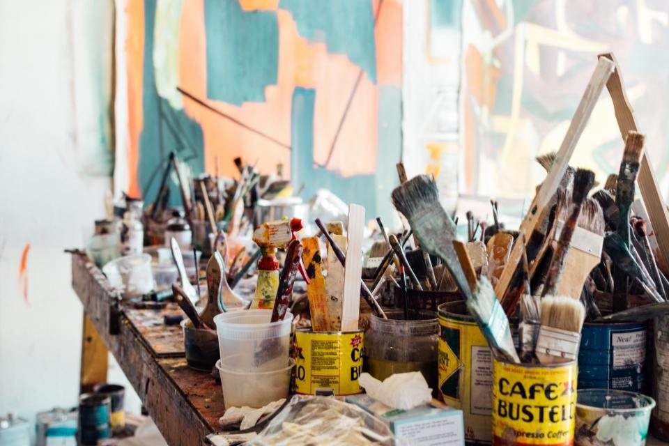 A studio table full of paints and brushes