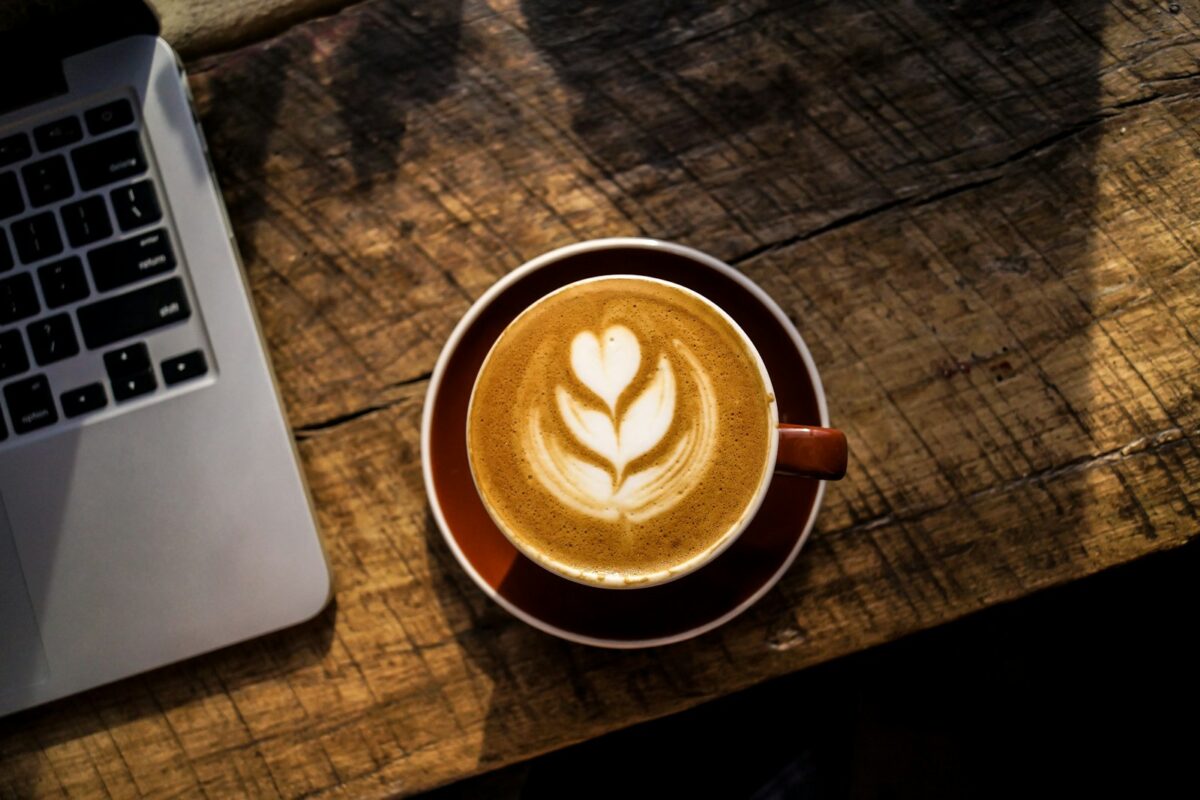 Latte on a wooden table next to a laptop