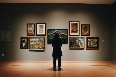 Visitor standing in a gallery room looking at a painting