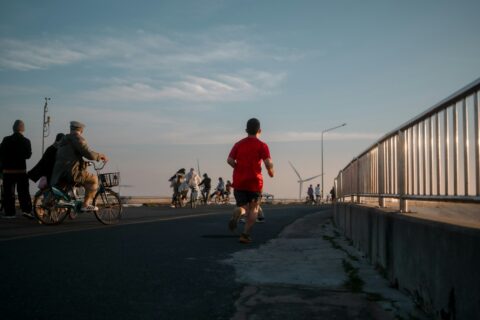 Man running along a riverside path among other people on a clear day